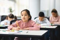 Portrait of asian girl sitting in classroom and writing Royalty Free Stock Photo