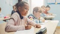 In Elementary School Classroom Brilliant Black Girl Writes in Exercise Notebook, Taking Test and W Royalty Free Stock Photo