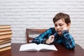 Elementary school kid biting a pen pondering over the task solut Royalty Free Stock Photo