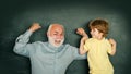 Elementary school kid and teacher with laptop in classroom at school. Grandfather with grandson learning lesson together Royalty Free Stock Photo