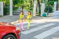 Elementary school kids crossing the street wearing a vest with the stop sine on it