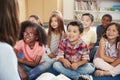 Elementary school kids sit on floor looking up at teacher Royalty Free Stock Photo