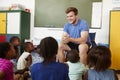 Elementary school kids sitting on floor listening a teacher Royalty Free Stock Photo