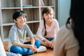 Elementary school kids sitting on the floor and looking at teacher in their classroom. The teacher is reading story tale from a Royalty Free Stock Photo