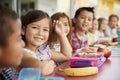 Elementary school kids sitting a table with packed lunches