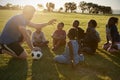 Elementary school kids and teacher sitting with ball in field Royalty Free Stock Photo