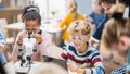 Elementary School Science Classroom: Cute Little Girl Looks Under Microscope, Boy Uses Digital Royalty Free Stock Photo