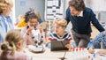 Elementary School Science Classroom: Cute Little Girl Looks Under Microscope, Boy Uses Digital Royalty Free Stock Photo