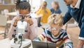 Elementary School Science Classroom: Cute Little Girl Looks Under Microscope, Boy Uses Digital Royalty Free Stock Photo