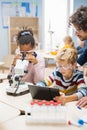 Elementary School Science Classroom: Cute Little Girl Looks Under Microscope, Boy Uses Digital Royalty Free Stock Photo