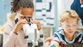 Elementary School Science Classroom: Cute Little Girl Looks Under Microscope, Boy Uses Digital Royalty Free Stock Photo