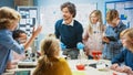 Elementary School Science Classroom: Enthusiastic Teacher Explains Chemistry to Diverse Group of Royalty Free Stock Photo