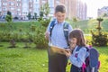 Elementary school students with a textbook outdoors. Back to school