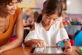 Elementary School Teacher And Female Pupil Drawing Using Digital Tablet In Classroom Royalty Free Stock Photo