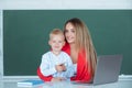 Elementary school teacher and pupil in classroom. Mother and son together using computer laptop. Royalty Free Stock Photo