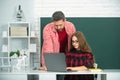 Elementary school teacher and pupil doing homework using computer laptop in classroom. Royalty Free Stock Photo