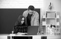 Elementary school teacher and pupil doing homework using computer laptop in classroom. Royalty Free Stock Photo