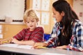 Elementary school teacher working at desk with schoolboy Royalty Free Stock Photo