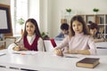 Elementary or secondary school girl pupils sitting at desk in classroom portrait