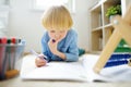 Elementary student boy doing homework at home. Child learning to count, solves arithmetic examples, doing exercises in workbook. Royalty Free Stock Photo