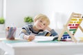 Elementary student boy doing homework at home. Child learning to count, solves arithmetic examples, doing exercises in workbook. Royalty Free Stock Photo