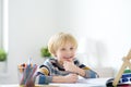 Elementary student boy doing homework at home. Child learning to count, solves arithmetic examples, doing exercises in workbook. Royalty Free Stock Photo