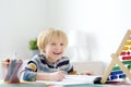 Elementary student boy doing homework at home. Child learning to count, solves arithmetic examples, doing exercises in workbook. Royalty Free Stock Photo