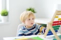 Elementary student boy doing homework at home. Child learning to count, solves arithmetic examples, doing exercises in workbook. Royalty Free Stock Photo