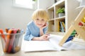 Elementary student boy doing homework at home. Child learning to count, solves arithmetic examples, doing exercises in workbook. Royalty Free Stock Photo