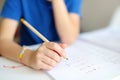 Elementary student boy doing homework at home. Child learning to count, solves arithmetic examples, doing exercises in workbook. Royalty Free Stock Photo