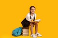 Elementary Student Girl Reading Sitting On Books Stack, Yellow Background Royalty Free Stock Photo