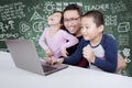 Elementary students using a laptop with their teacher Royalty Free Stock Photo