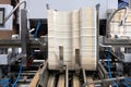 Elements of corton boxes are collected in stack. Conveyor line for the production of boxes. Machine cuts cardboard boxes from shee
