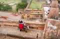 Elephant carries tourists up the hill past the stone walls of the fortress