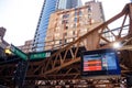 Elevated `el` tracks on the corner of Washington & Wells St with train tracker sign in Chicago Loop