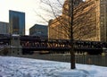 Elevated `el` train passes over the Chicago River and a snow covered Riverwalk in winter. Royalty Free Stock Photo