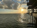 Elevated metal pier silhouetted against an orange-hued sunset sky with wispy clouds