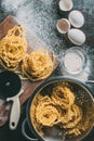 elevated view of adjustable dough cutter, raw pasta, colander, sieve, egg shells and eggs on table covered