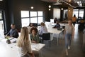 Elevated view of creative business colleagues working at desks and walking through a busy office Royalty Free Stock Photo