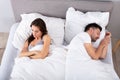 Woman lying on bed with her husband sleeping at home Royalty Free Stock Photo