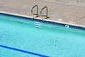Elevated view of the outdoor swimming pool with metal handrails with steps, depth marker on the pool edge, underwater light Royalty Free Stock Photo