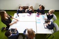 Elevated view of primary school kids sitting around a table in the classroom with their female teacher Royalty Free Stock Photo