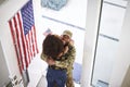 Elevated view of returning African American male soldier embracing his wife in the doorway of their home