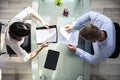 Elevated View Of Two Businesspeople Holding Resume