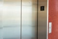 An elevator door and button next to a red wall Royalty Free Stock Photo