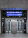 Elevator front view with glass in modern train station in Switzerland in the night. Above are the indications on a blue sign