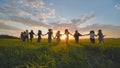 Eleven cheerful girls run to the meeting across the field in the summer, holding hands. Royalty Free Stock Photo