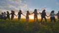 Eleven cheerful girls run to the meeting across the field in the summer, holding hands. Royalty Free Stock Photo