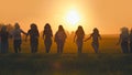 Eleven cheerful girls run to the meeting across the field in the summer, holding hands. Royalty Free Stock Photo