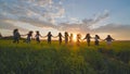 Eleven cheerful girls run to the meeting across the field in the summer, holding hands. Royalty Free Stock Photo